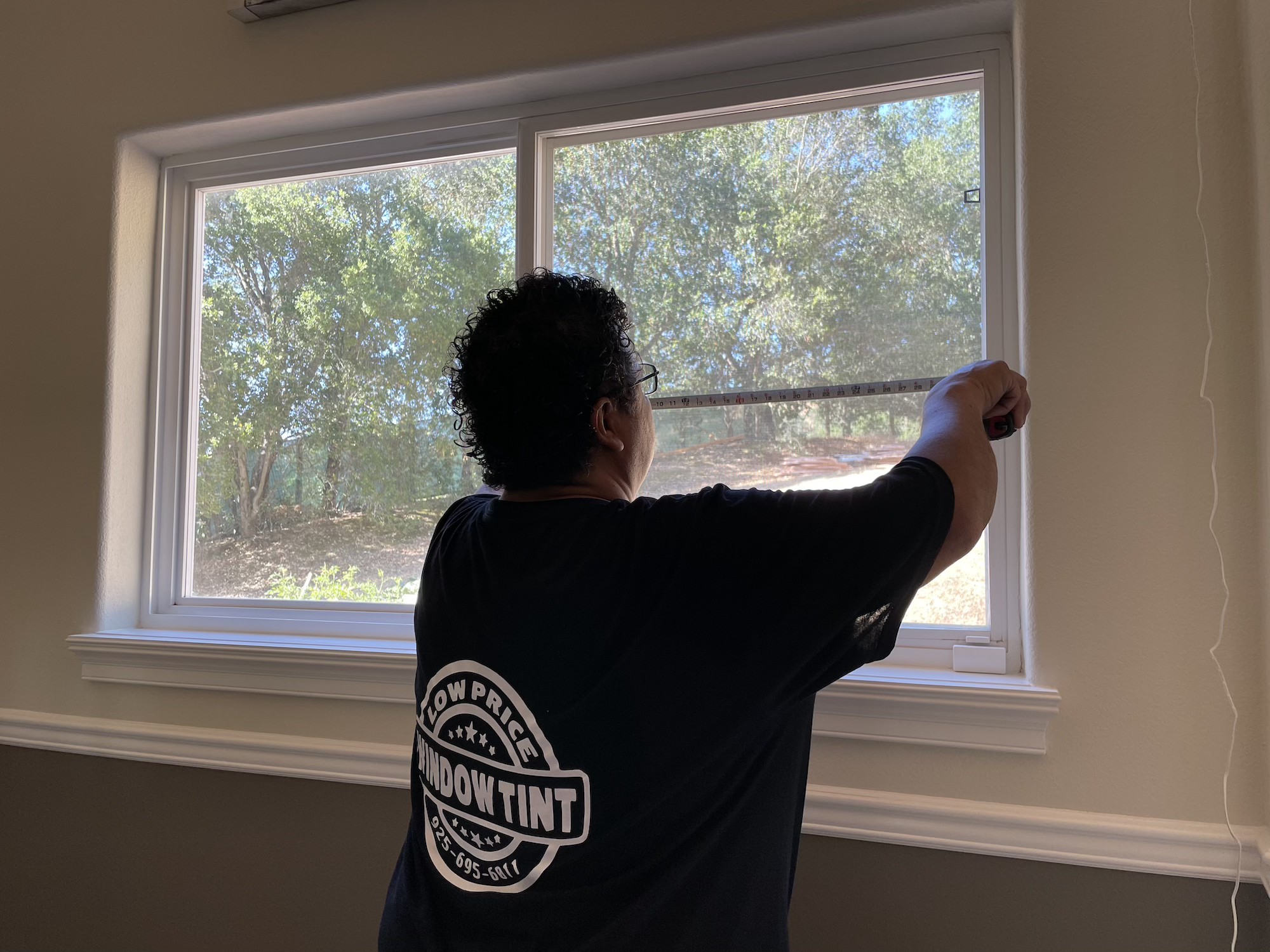 Low Price Window Tint technician measuring a large residential window in a Dublin, CA home before applying Solar Gard film